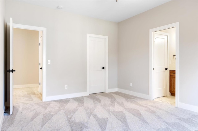 unfurnished bedroom with ensuite bath and light colored carpet