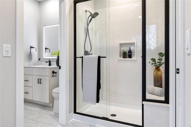 bathroom featuring a shower with door, vanity, and toilet