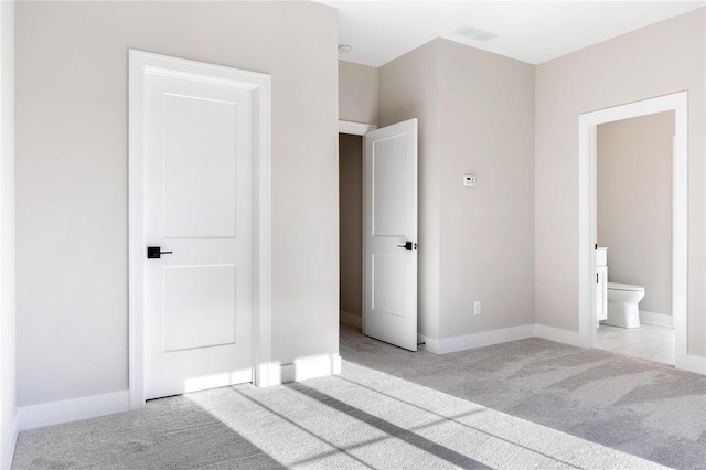 unfurnished bedroom featuring light carpet and connected bathroom