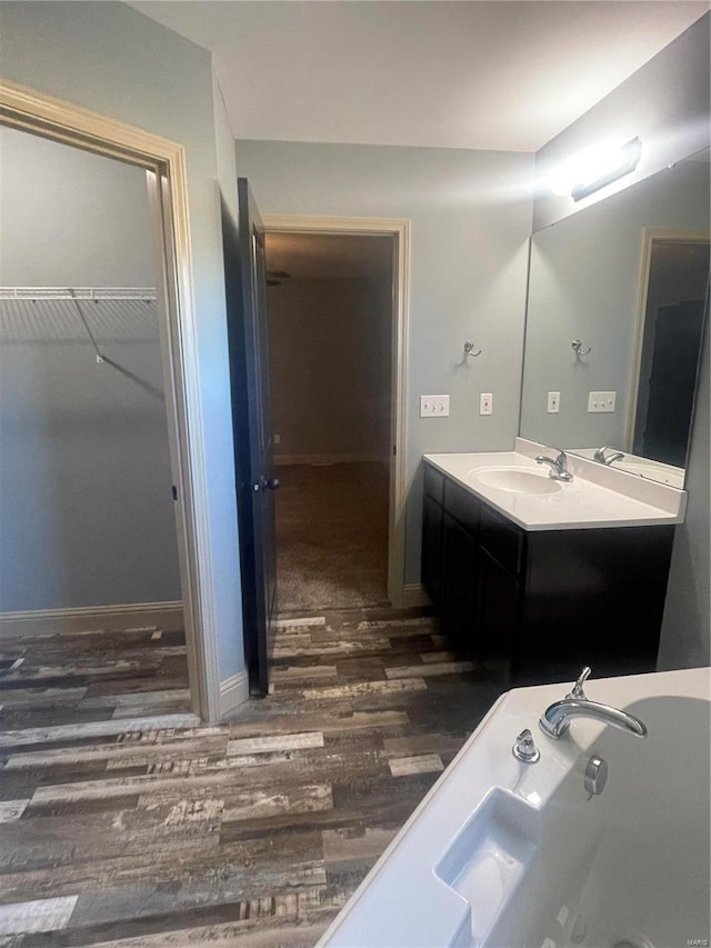 bathroom featuring wood-type flooring, vanity, and a tub