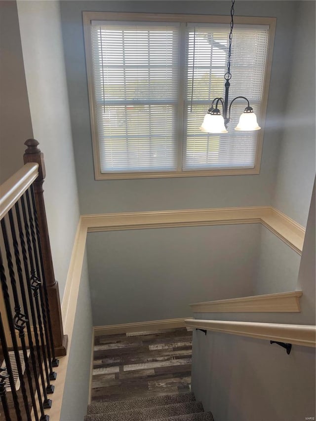 staircase with hardwood / wood-style flooring, plenty of natural light, and a notable chandelier