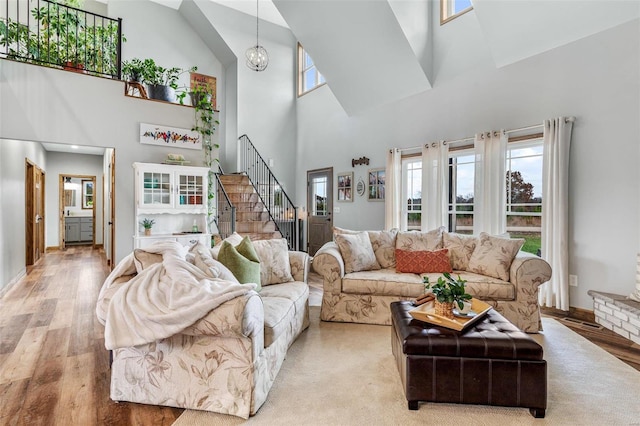 living room with an inviting chandelier, light hardwood / wood-style flooring, and high vaulted ceiling