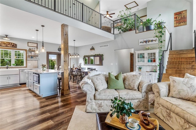 living room with sink, hardwood / wood-style floors, ceiling fan, and a towering ceiling