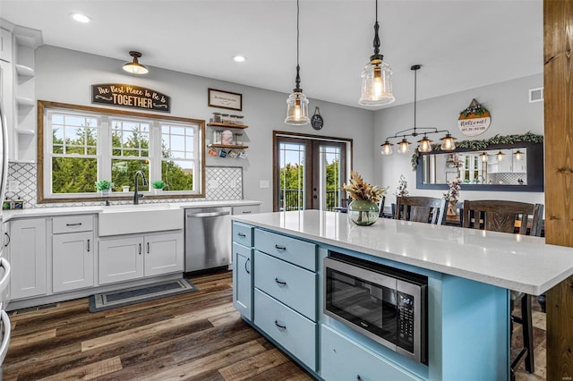 kitchen with white cabinets, decorative backsplash, a breakfast bar area, appliances with stainless steel finishes, and decorative light fixtures