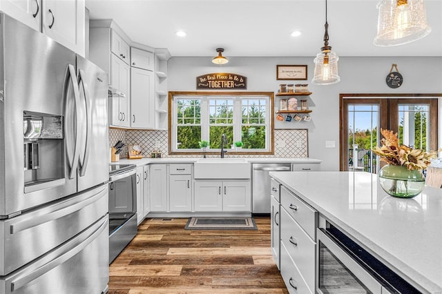 kitchen with white cabinetry, appliances with stainless steel finishes, dark hardwood / wood-style flooring, pendant lighting, and decorative backsplash