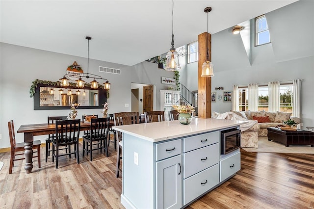 kitchen featuring stainless steel microwave, light hardwood / wood-style floors, and decorative light fixtures