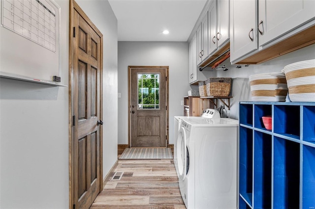 laundry area with cabinets, washer and dryer, and light wood-type flooring