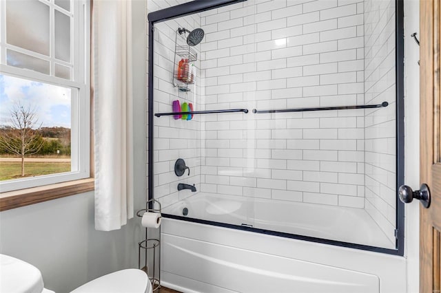 bathroom with toilet and combined bath / shower with glass door