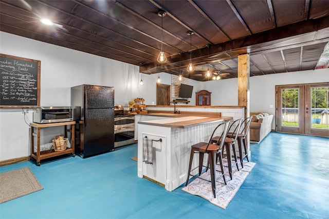 kitchen with black fridge, stainless steel range with electric cooktop, french doors, sink, and a breakfast bar area