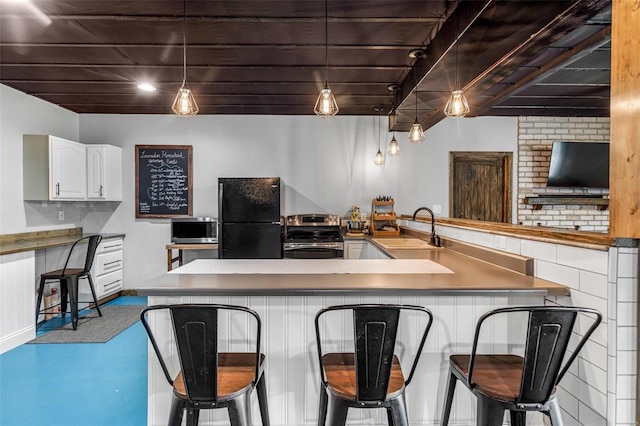 kitchen with a kitchen bar, stainless steel appliances, white cabinets, sink, and pendant lighting