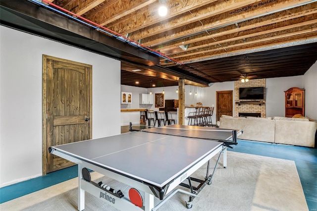 recreation room featuring a brick fireplace, concrete flooring, and ceiling fan