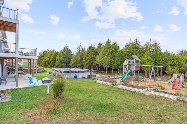 view of jungle gym featuring a patio, a yard, and a deck