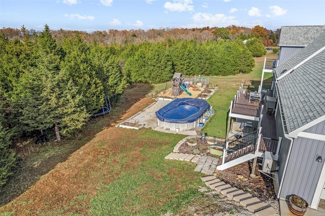 view of swimming pool featuring a playground, a patio area, a yard, and a deck