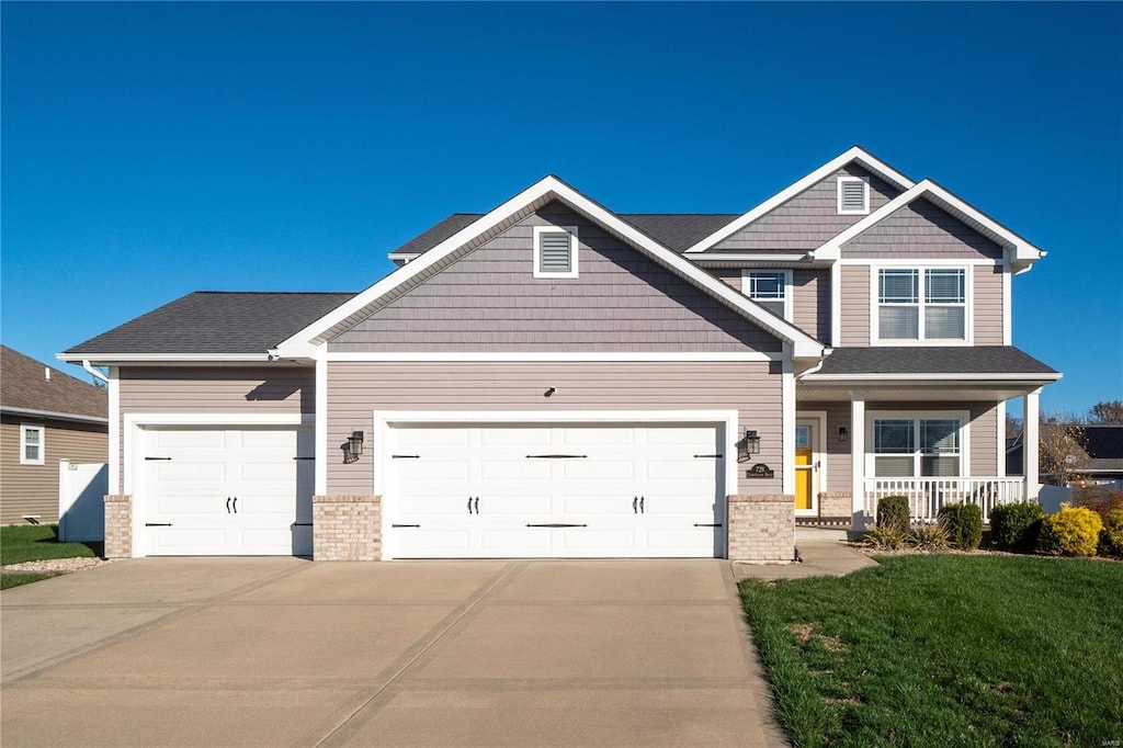 craftsman-style home with a front lawn, covered porch, and a garage