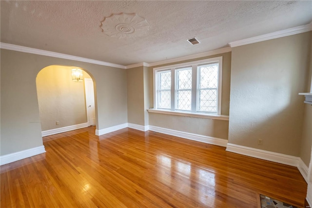 empty room with hardwood / wood-style floors, ornamental molding, and a textured ceiling