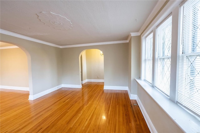 spare room featuring hardwood / wood-style flooring, plenty of natural light, and crown molding