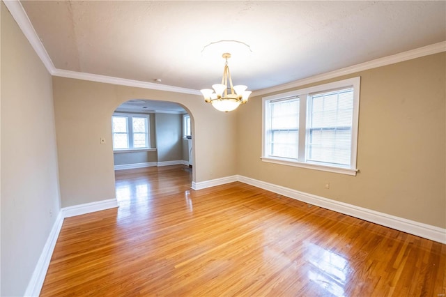 spare room with hardwood / wood-style flooring, an inviting chandelier, and crown molding