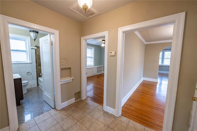 hallway featuring light hardwood / wood-style flooring, a healthy amount of sunlight, and ornamental molding