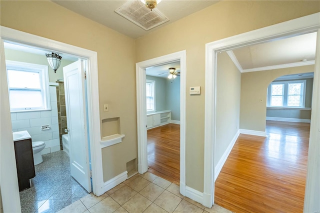 hall with crown molding, tile walls, and light wood-type flooring