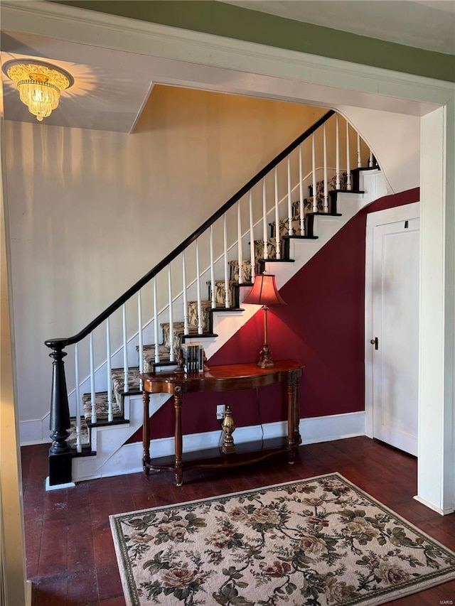 staircase with a chandelier, baseboards, and wood finished floors