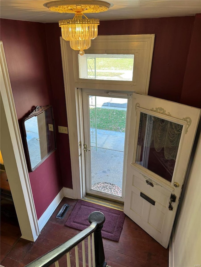 doorway to outside featuring an inviting chandelier, baseboards, and dark wood-type flooring