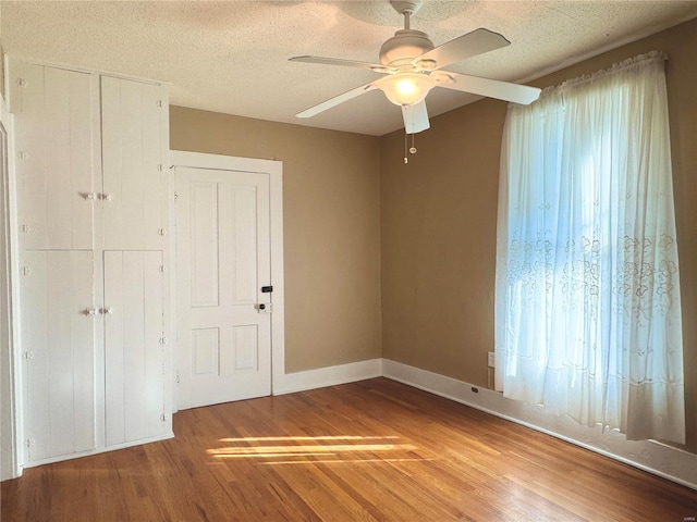 spare room with a ceiling fan, a textured ceiling, baseboards, and wood finished floors