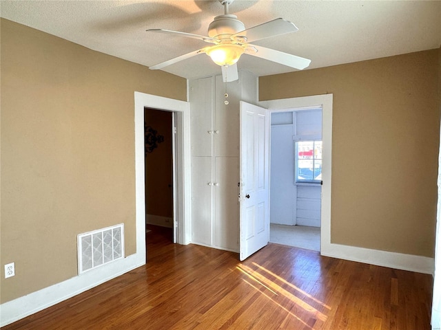 spare room with baseboards, visible vents, ceiling fan, wood finished floors, and a textured ceiling