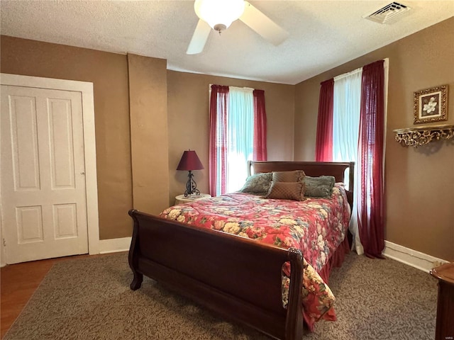 bedroom featuring baseboards, visible vents, ceiling fan, and a textured ceiling