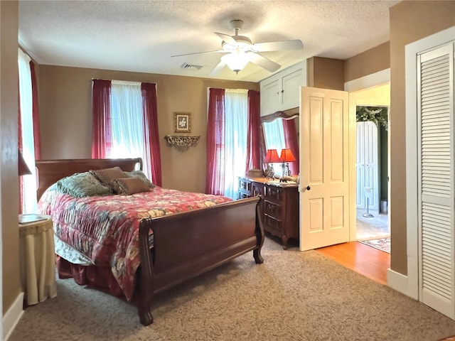 bedroom with ceiling fan, multiple windows, visible vents, and a textured ceiling