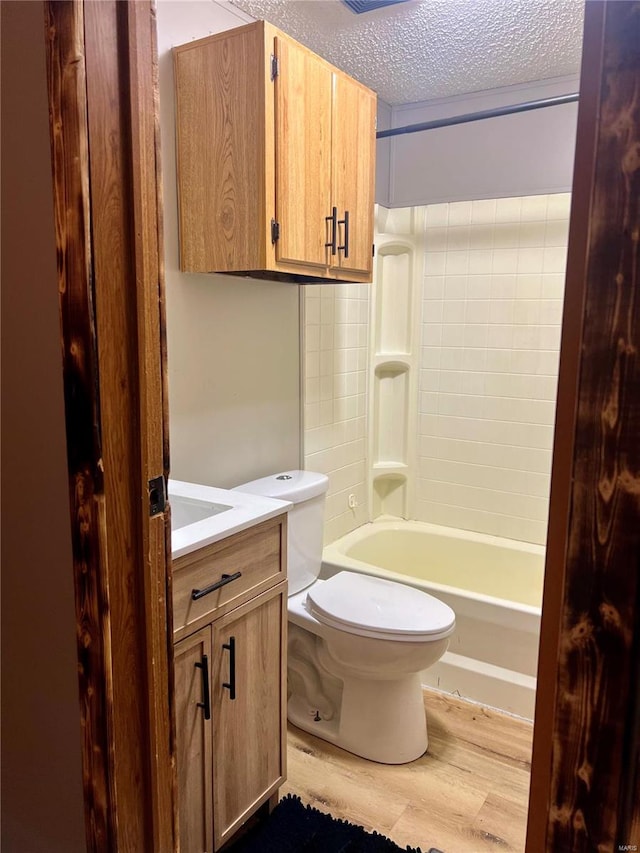 full bathroom featuring hardwood / wood-style flooring, toilet, shower / bath combination, vanity, and a textured ceiling