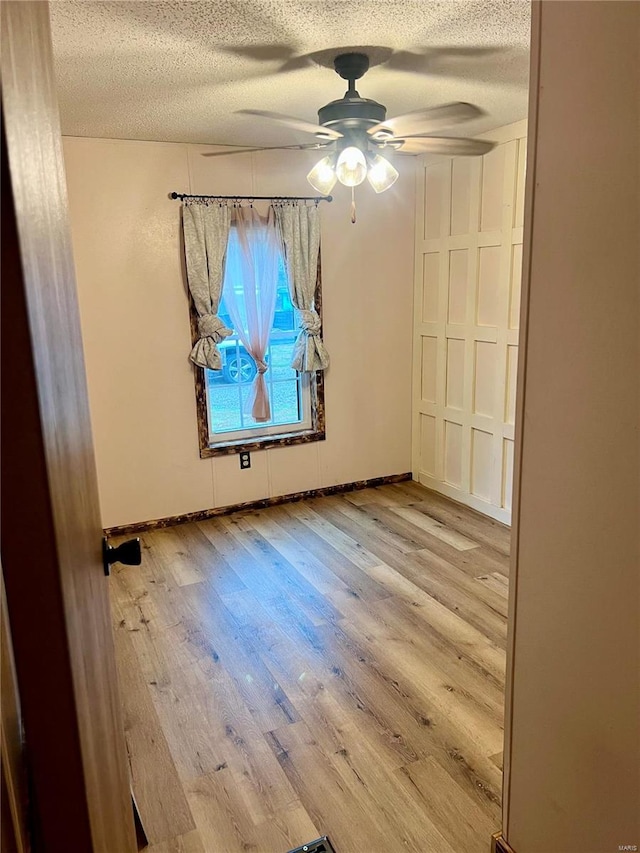 spare room featuring ceiling fan, a textured ceiling, and light wood-type flooring