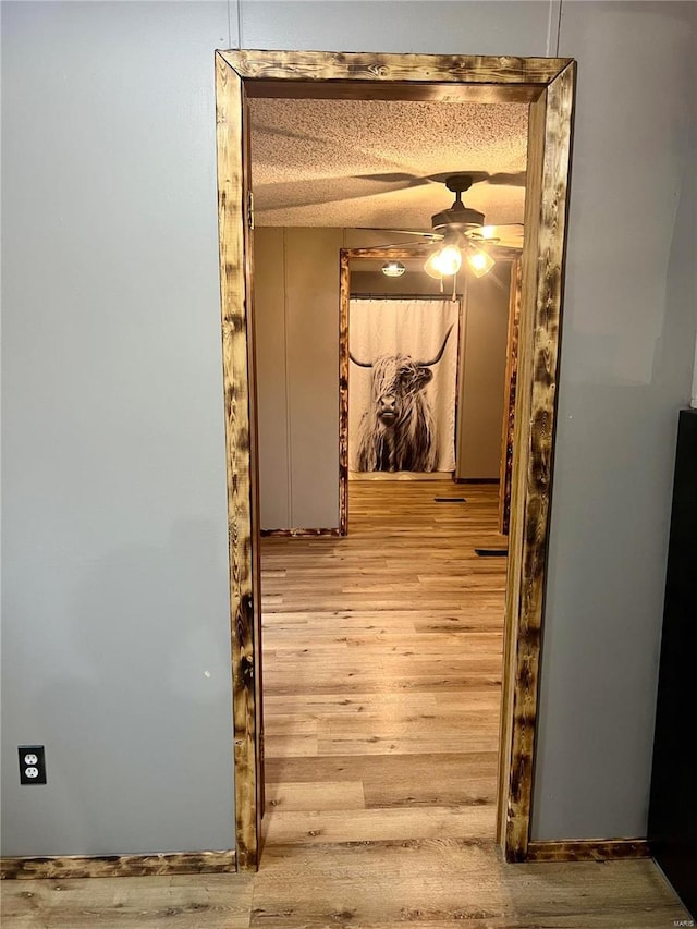 hall with a textured ceiling and wood-type flooring