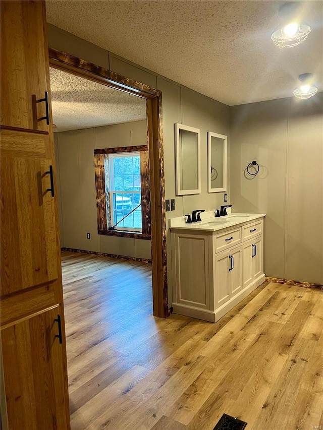 bathroom featuring beamed ceiling, vanity, hardwood / wood-style floors, and a textured ceiling