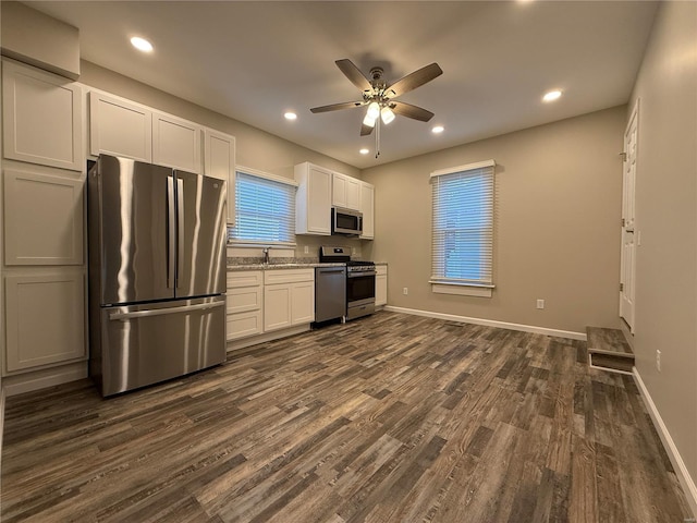 kitchen featuring white cabinetry, stainless steel appliances, dark wood-type flooring, and light stone countertops