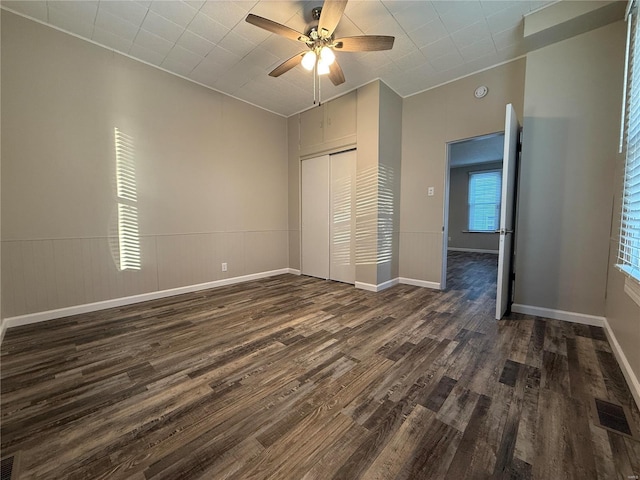 unfurnished bedroom featuring dark wood-type flooring, ceiling fan, and a closet