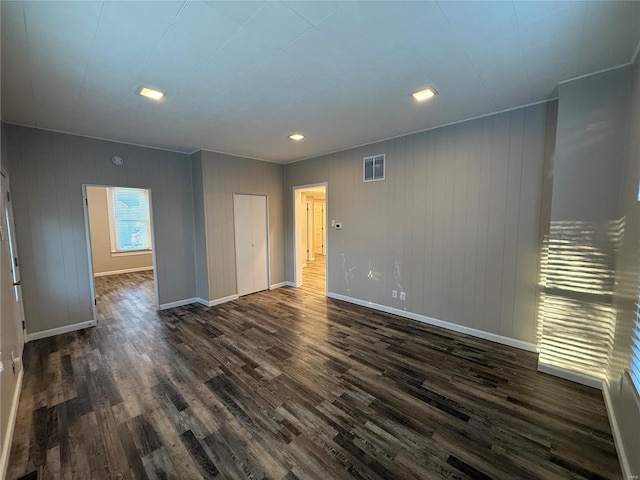 empty room with dark wood-type flooring and wooden walls