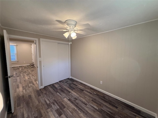 unfurnished bedroom with ceiling fan, dark hardwood / wood-style floors, a closet, and ornamental molding