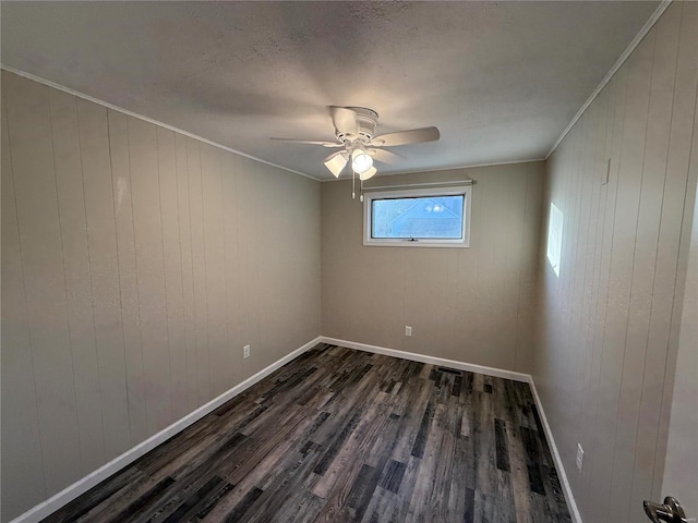 unfurnished room with ornamental molding, dark hardwood / wood-style flooring, wood walls, and ceiling fan