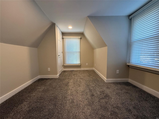 bonus room featuring dark colored carpet and vaulted ceiling