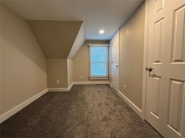 additional living space featuring dark colored carpet and lofted ceiling