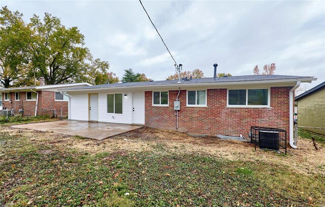 rear view of property featuring a yard, central AC unit, and a patio area