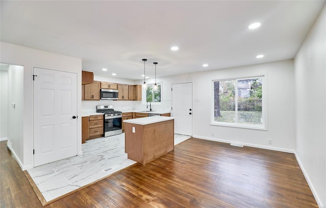 kitchen featuring pendant lighting, sink, appliances with stainless steel finishes, a center island, and light wood-type flooring