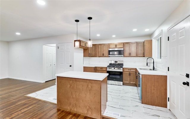 kitchen with pendant lighting, sink, backsplash, stainless steel appliances, and a center island