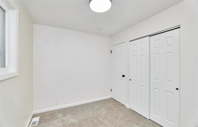 unfurnished bedroom featuring light colored carpet and a closet