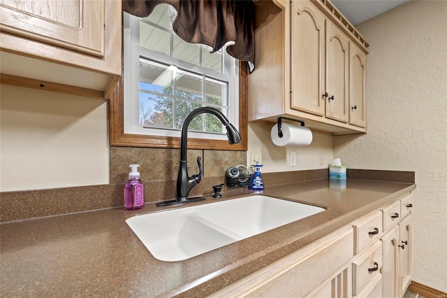 kitchen with light brown cabinets, decorative backsplash, a textured ceiling, and sink