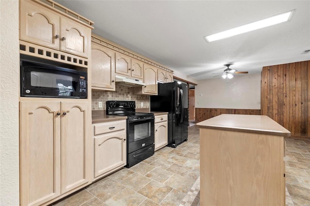 kitchen featuring wood walls, black appliances, tasteful backsplash, light brown cabinets, and a center island