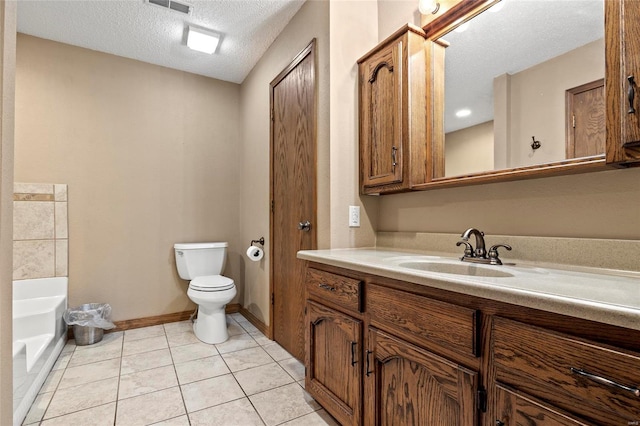 bathroom featuring toilet, tile patterned flooring, a textured ceiling, vanity, and a tub to relax in