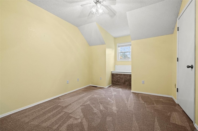 additional living space featuring carpet, a textured ceiling, vaulted ceiling, and ceiling fan