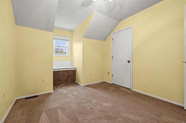 bonus room with light colored carpet, a textured ceiling, and lofted ceiling