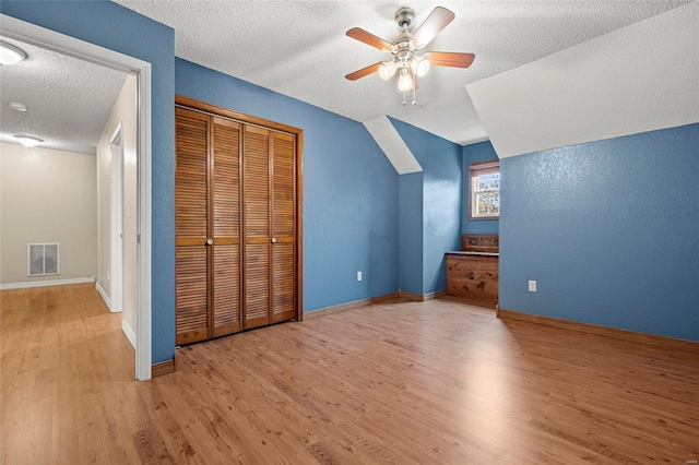 additional living space featuring ceiling fan, a textured ceiling, light hardwood / wood-style flooring, and lofted ceiling